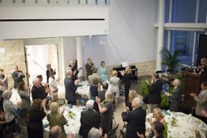 President Pamela Fox (in front, wearing light blue dress) receives a standing ovation during a dinner to celebrate MDCHS. 